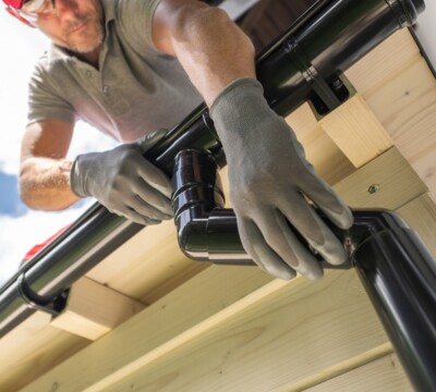 Worker Installing Gutter System on Roof